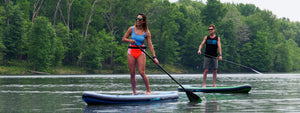 Inflatable touring sup at a lake on still green water
