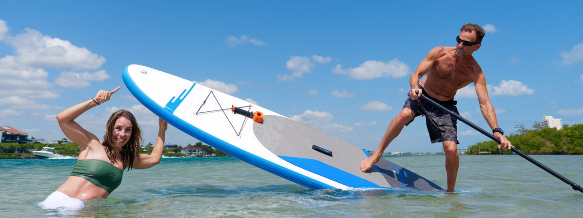 Girl pointing at a paddle board with guy riding it