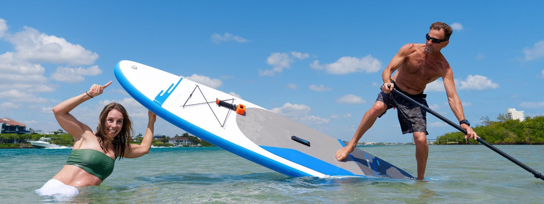 Girl pointing at a paddle board with guy riding it